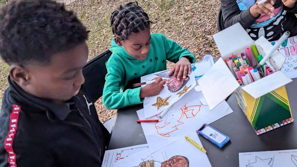 Three children at Disston Place Apartments creating art honoring Dr. Martin Luther King, Jr.