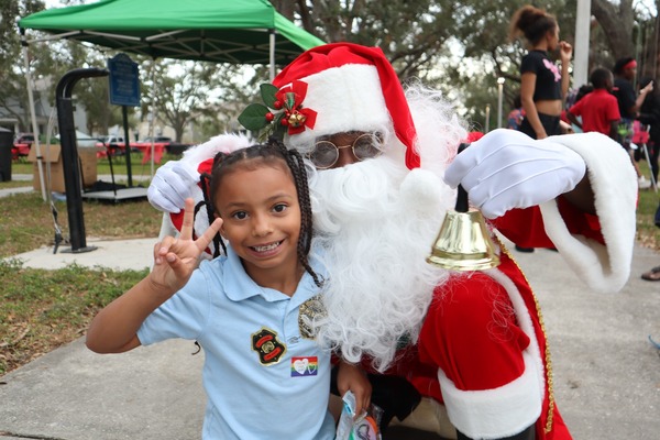 Child wearing light blue shirt with Santa Claus at Very Merry Holiday Party in Jordan Park.