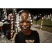 Child with their face painted and candy cane decorations in the background at Very Merry Holiday Party in Jordan Park.