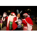 Mr. and Mrs. Santa Claus and woman wearing blue reindeer antlers waving.